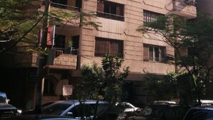 A multi-story residential building with balconies, parked cars, and surrounding greenery. - A Cosy Three Bedrooms  Apartment in Degla, Maadi ,Cairo, Egypt. (Maadi)