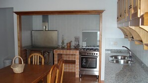 A compact kitchen with a dining table, chairs, a stove, oven, and a sink.