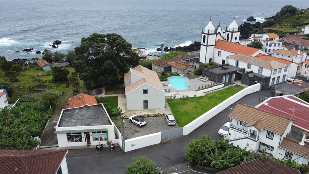 A coastal village with a prominent church, a swimming pool, and residential buildings.