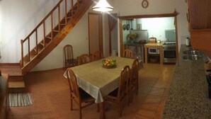 A dining area with a wooden staircase, a kitchen with a stove and microwave, and a small sink.
