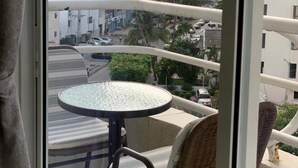 Ein Balkon mit rundem Tisch und Korbstühlen, Blick auf eine Skyline mit hohen Gebäuden und Palmen.