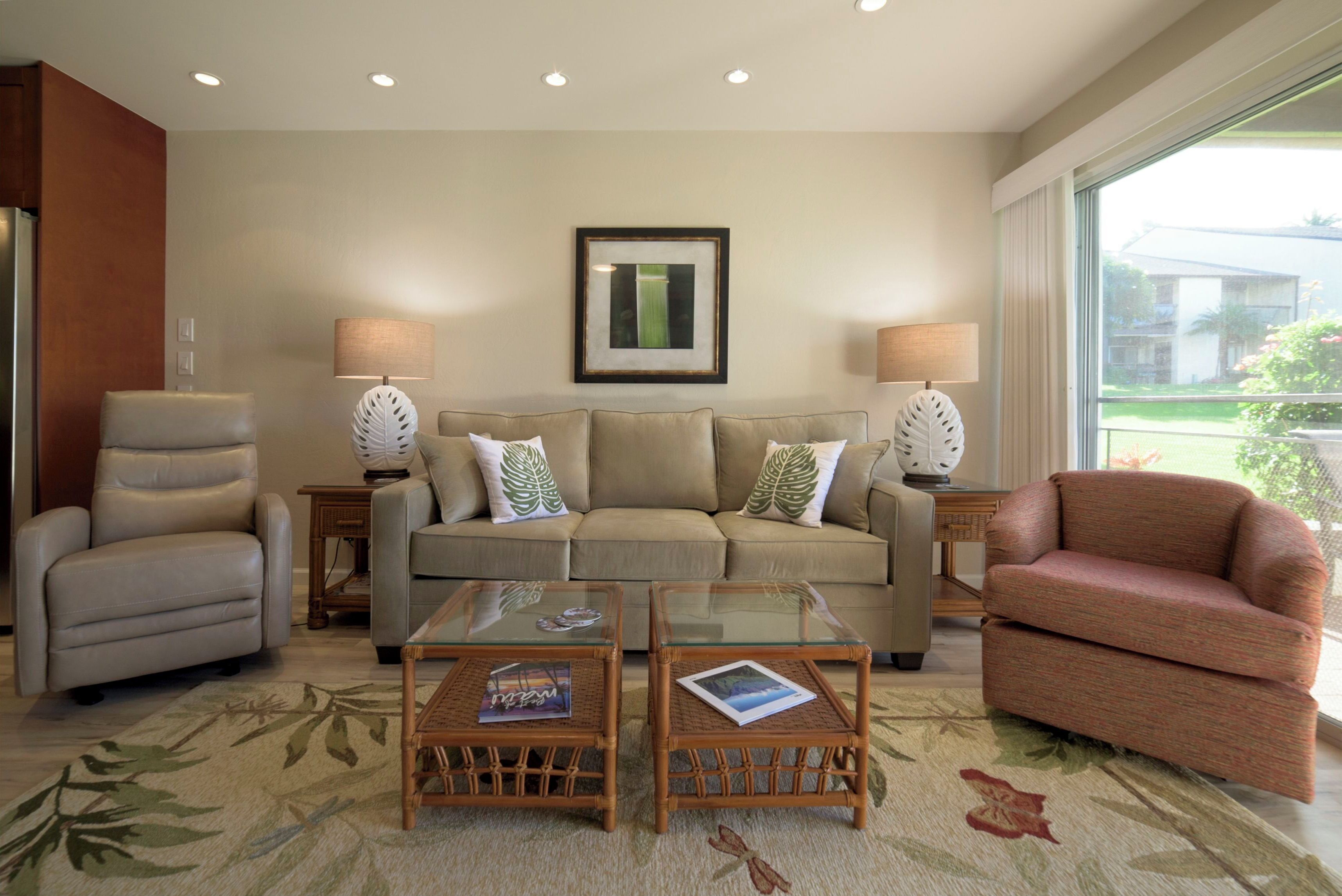 A living room with a sofa, two armchairs, a glass coffee table, and two side tables with lamps.