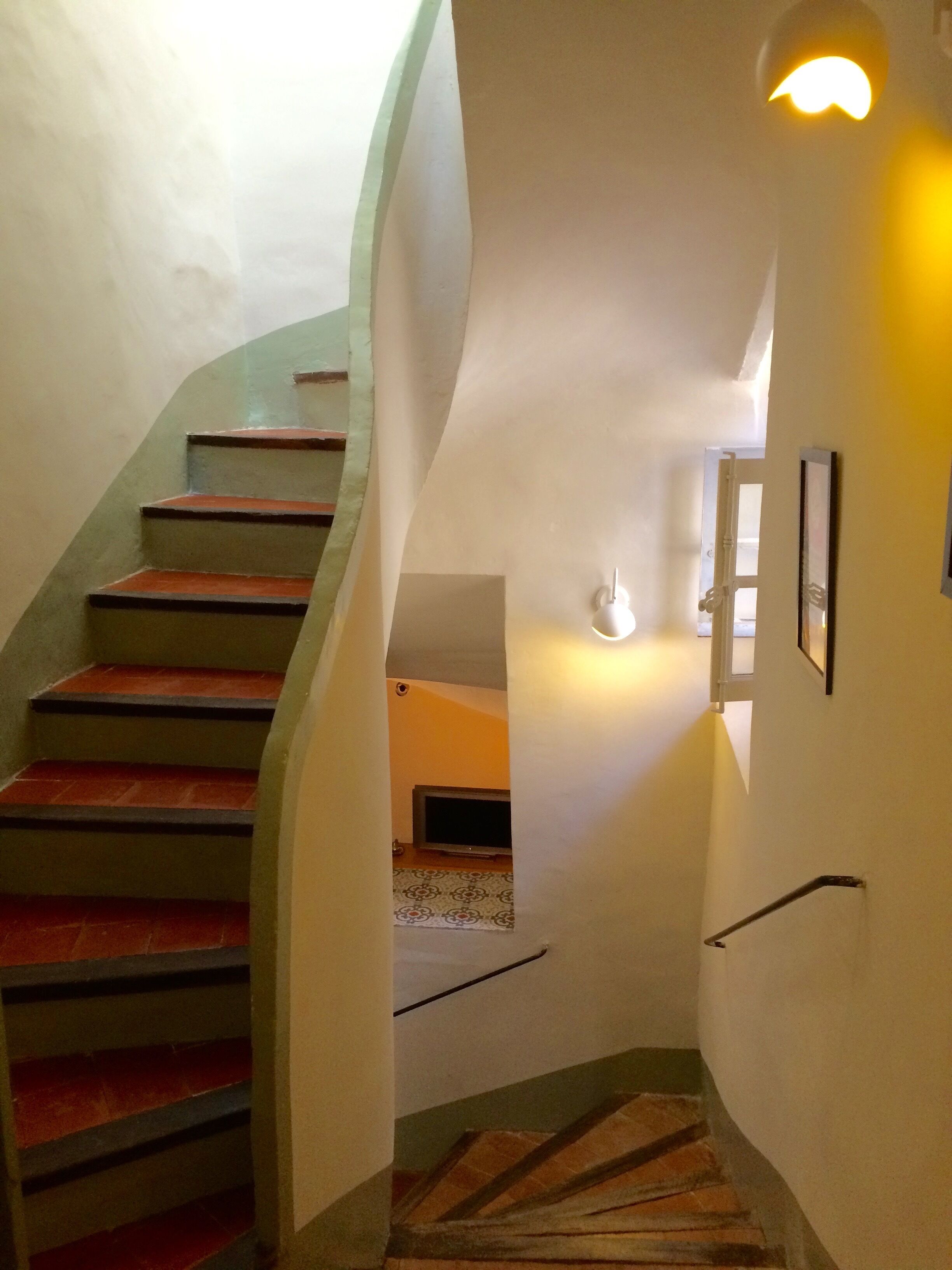 Un escalier en colimaçon avec des marches rouges menant à un palier.