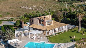 Ein großes Haus mit Swimmingpool, Sitzgelegenheiten im Freien und einer überdachten Terrasse.