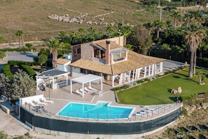 A large house with a swimming pool, outdoor seating, and a covered patio.