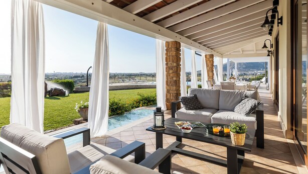 Eine Außenpatio mit Pool, einer Couch und einem Tisch mit einer Speisenauswahl.