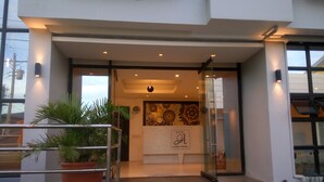 A hotel entrance with a glass door, steps leading up to it, and potted plants on the left. - Hotel Rupert A Baler (Baler)