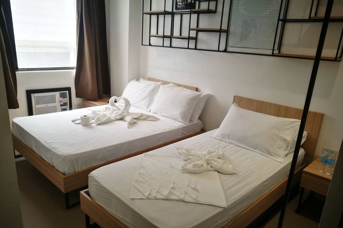 Two single beds with white linens and towels arranged in swan shapes.