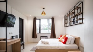 A modern bedroom with a bed, a desk, a TV, and a window with curtains. - Hotel Rupert A Baler (Baler)