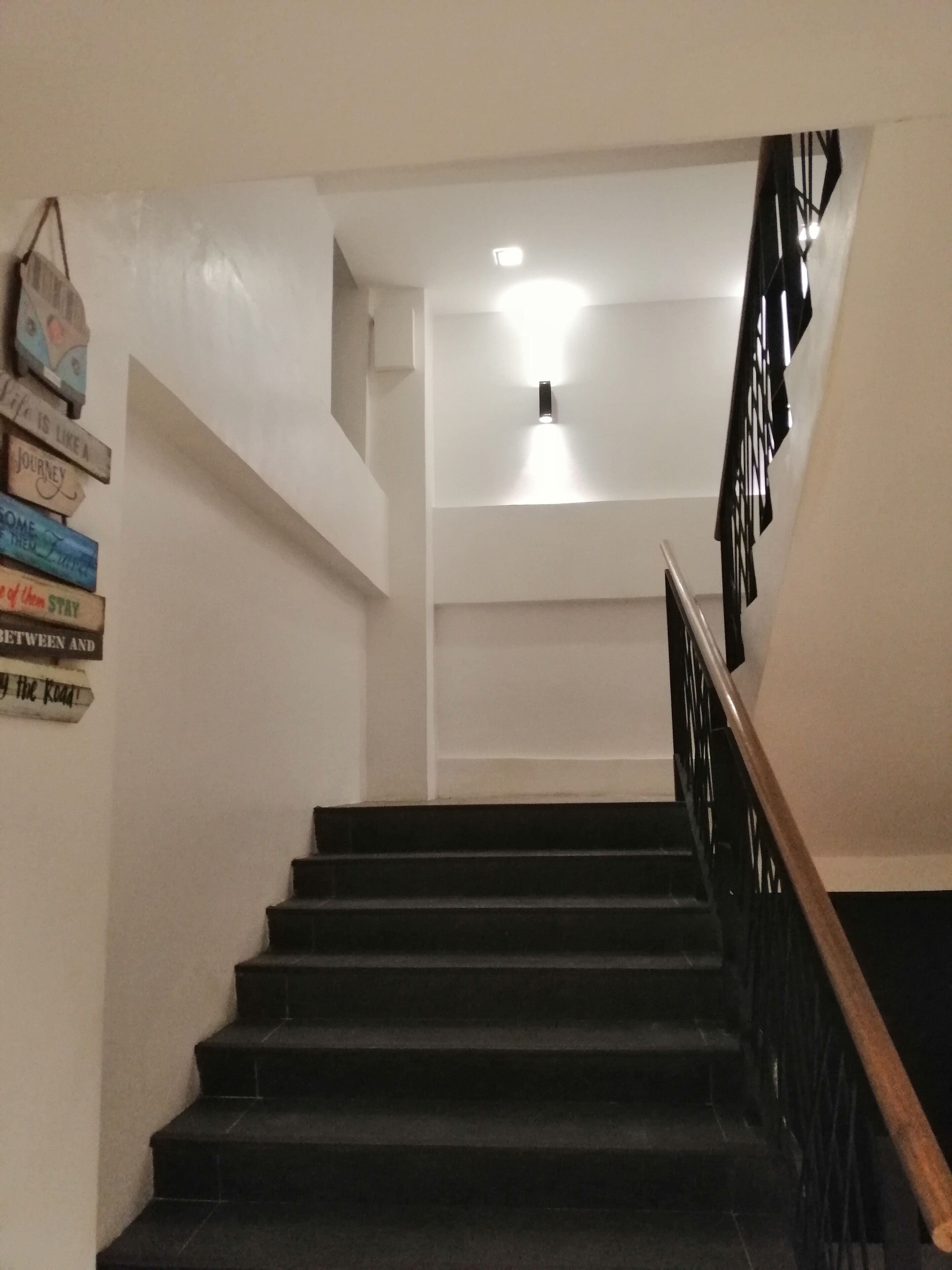 A staircase with a wooden handrail and black steps leading up to a landing.