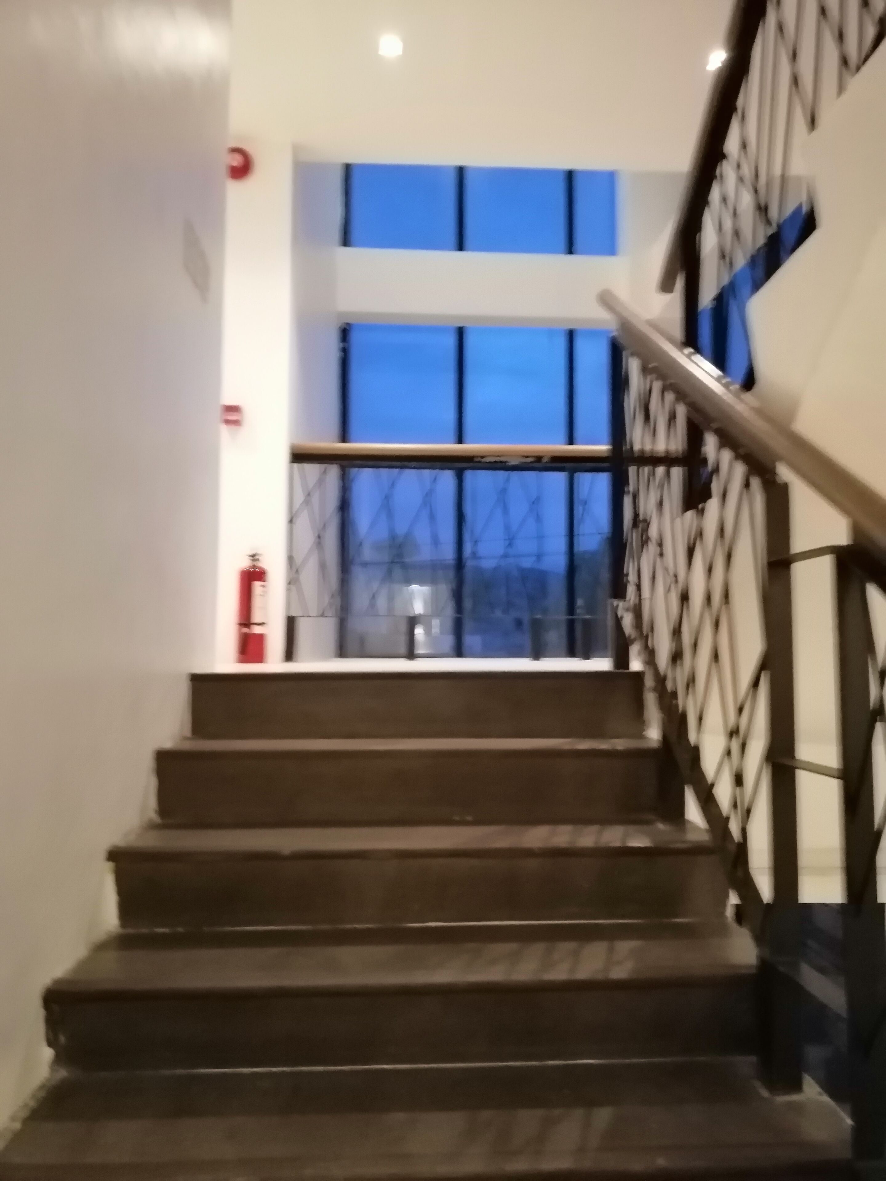 A staircase with a metal railing and a fire extinguisher on the wall.