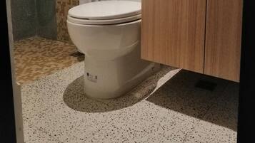A bathroom with a toilet, shower, and sink.