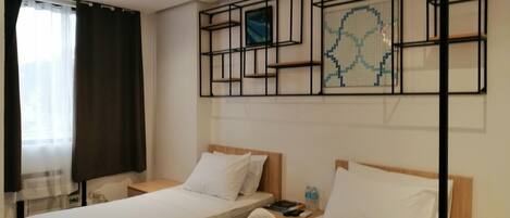 A hotel room with two beds, a wall-mounted artwork, and a ceiling light.