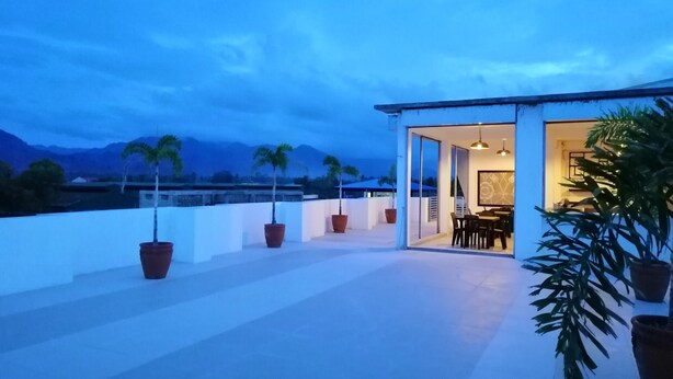A rooftop terrace with potted plants, a dining area, and a view of mountains. - Hotel Rupert A Baler (Baler)