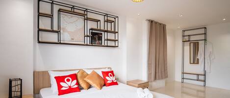 Una habitación de hotel moderna con una cama bien hecha, una mesita de noche, una bata colgada y un amplio ventanal con cortinas.