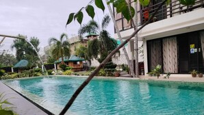 A swimming pool with clear water, surrounded by lush greenery and a building with a balcony. - Hotel Rupert A Baler (Baler)