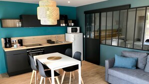 A compact living space with a kitchenette, a dining area, a sofa, and a large window. - CHARMING APARTMENT WITH TERRACE IN A QUIET RESIDENCE NEAR JONZAC CENTER (Jonzac)