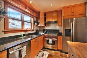 Enjoy cooking and food preparation in this kitchen with a large window offering a view of the surrounding landscape.