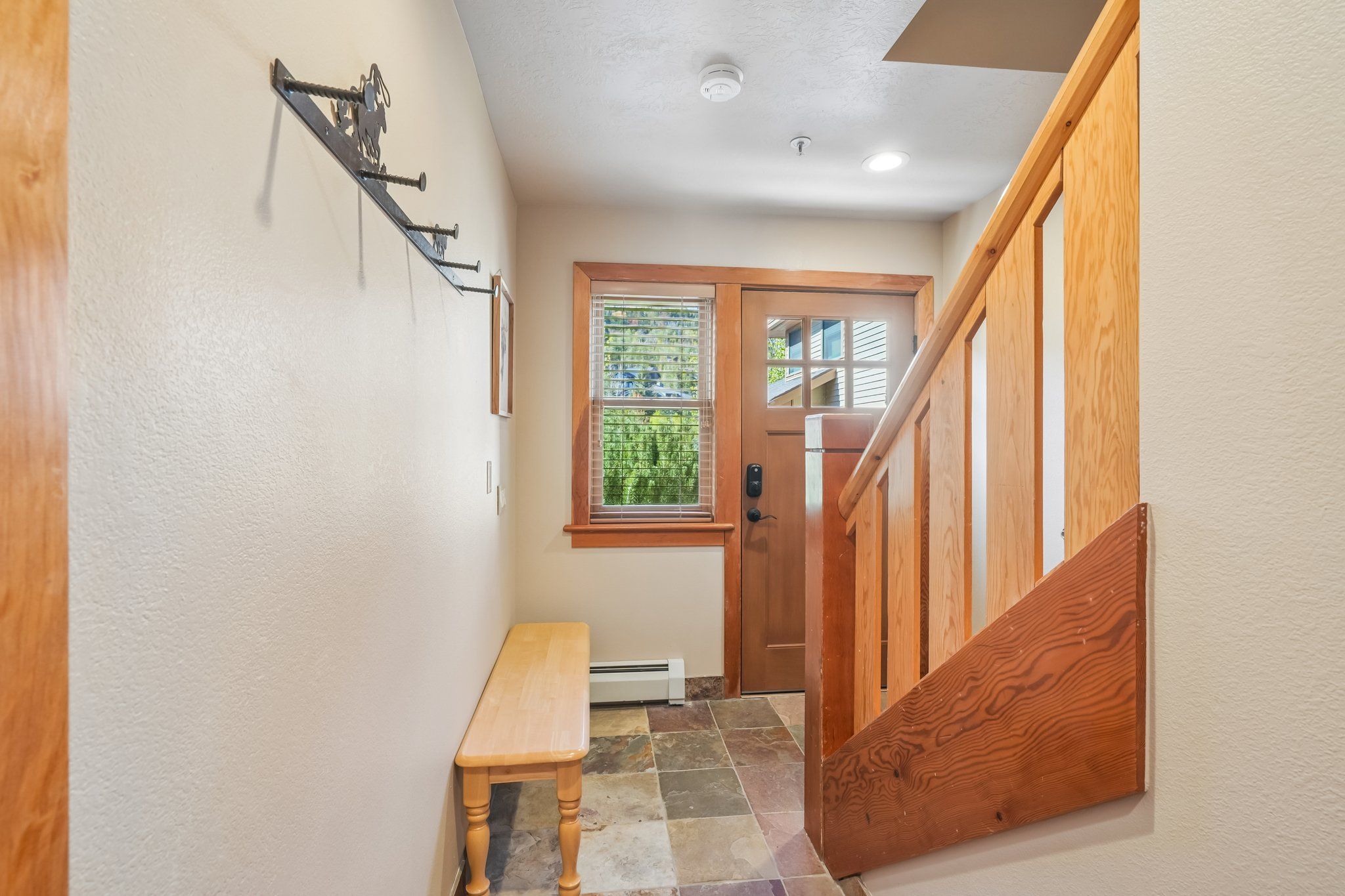 A hallway with a wooden bench, a door with a window, and a staircase.