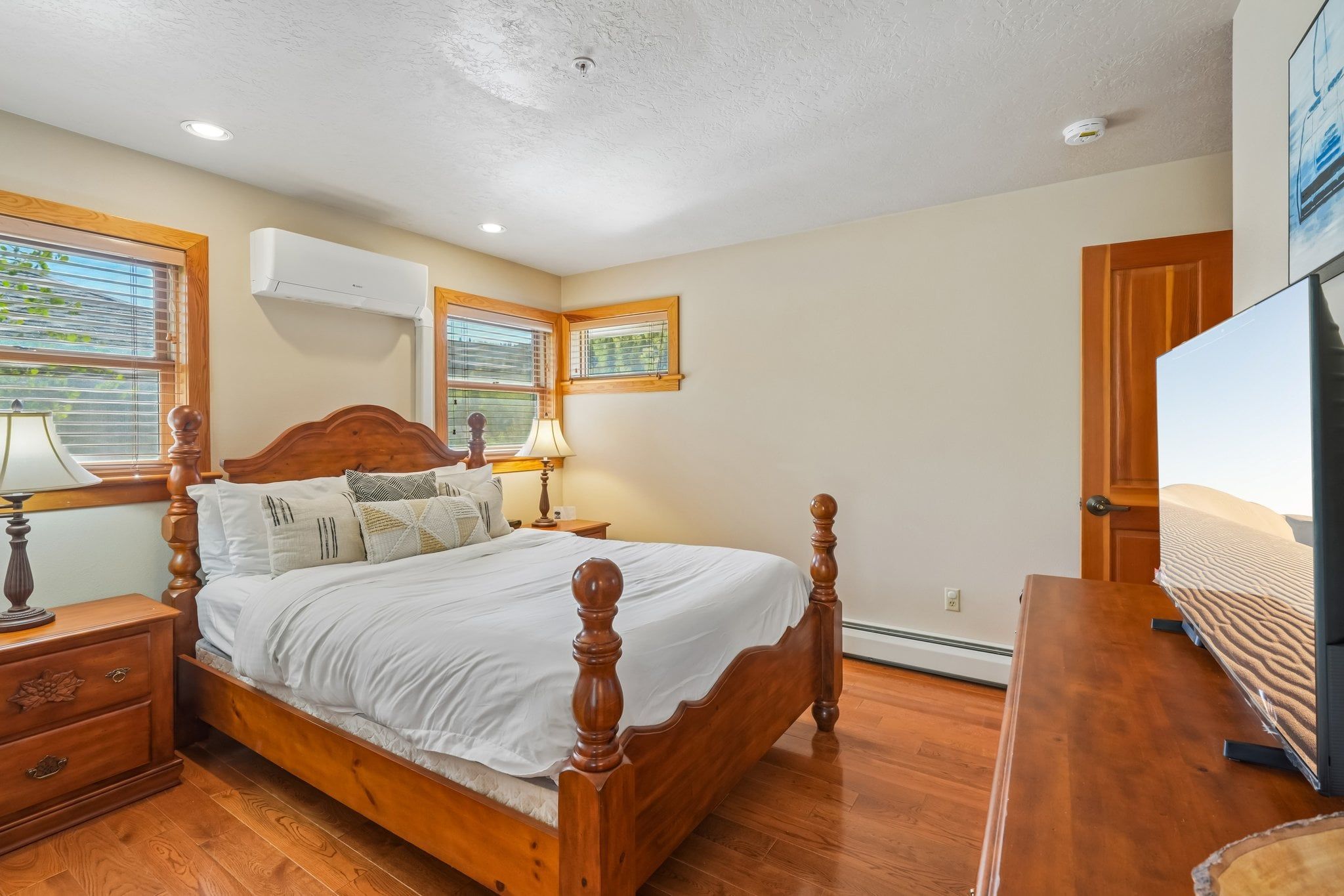 A bedroom with a wooden bed, bedside tables, a lamp, and a television.