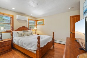 Une chambre à coucher avec un lit en bois, des tables de chevet, une lampe et un téléviseur.
