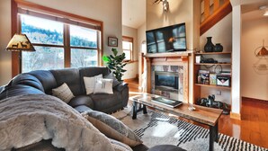Una sala de estar acogedora con chimenea, televisor y estantería.