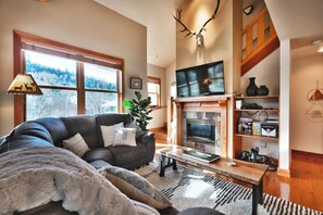 Relax in this inviting living room with a comfortable sofa, fireplace, and serene view.