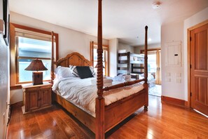 Relax in a serene bedroom with a four-poster bed, nightstand, and window with blinds.