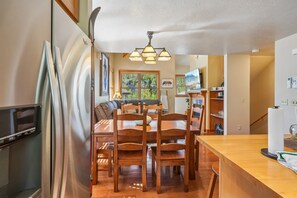 A compact kitchen with a dining area, wooden furniture, and a built-in TV.