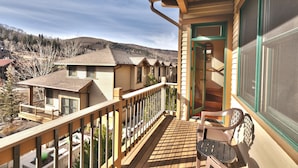 Una terraza de madera con vista a casas vecinas y una montaña al fondo.