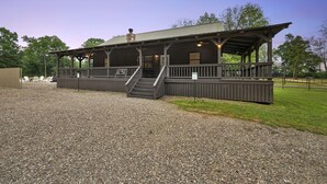 A wooden building with a covered porch and a staircase leading to the entrance. - Firefly at Lazy River Cabins on Mt Fork River (Broken Bow)