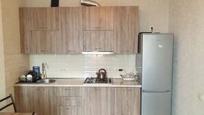 Keittiössä on puukaapit, pesuallas, kaasuliesi, vedenkeitin ja jääkaappi.