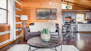 A cozy cabin interior with a living room featuring a sofa, a coffee table, and a painting of mountains. - Amazing Mt. LeConte Views/Gatlinburg Log Cabin (Gatlinburg)