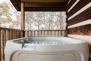 Un bain à remous sur une terrasse en bois, avec vue sur les arbres.