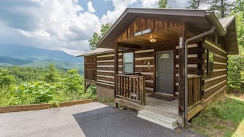 Une cabane rustique dotée d’une véranda, d’une porte et offrant une vue sur le paysage environnant.