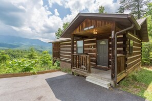 Une cabane rustique dotée d’une véranda, d’une porte et offrant une vue sur le paysage environnant.