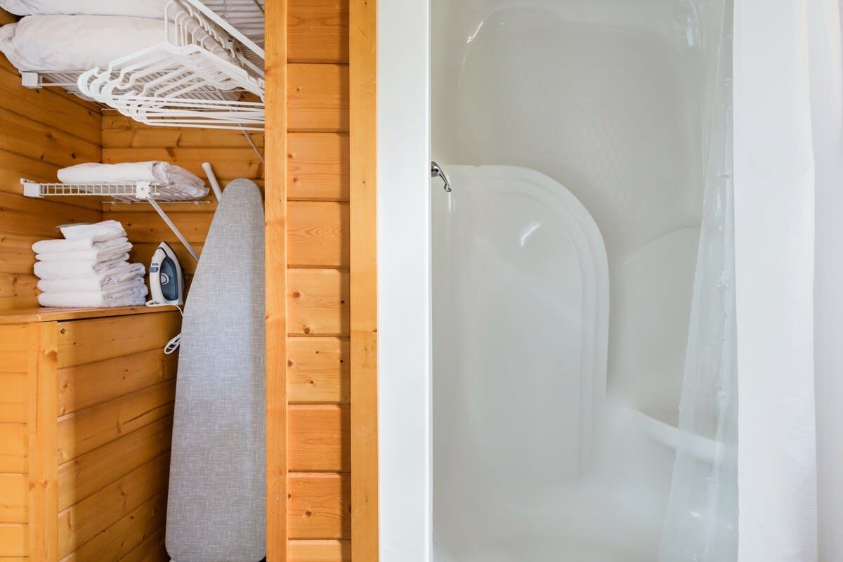 Eine Holzhütte mit einer weißen Badewanne, Handtüchern und einem Wäscheständer.