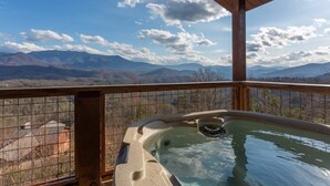 A hot tub with a view of mountains and a clear sky.