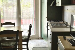Una cocina con estufa a gas, un lavamanos y una mesa de madera con sillas.