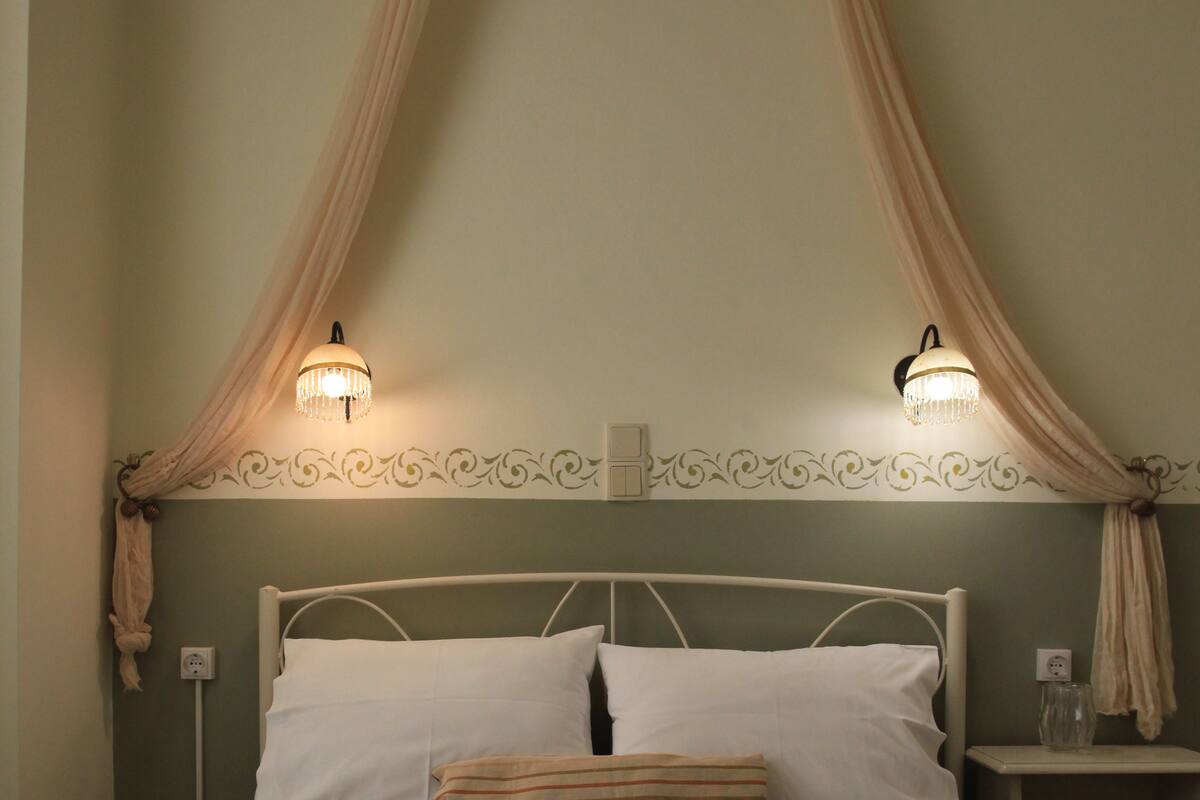 A bed with a canopy, two bedside lamps, a nightstand, and two towels.
