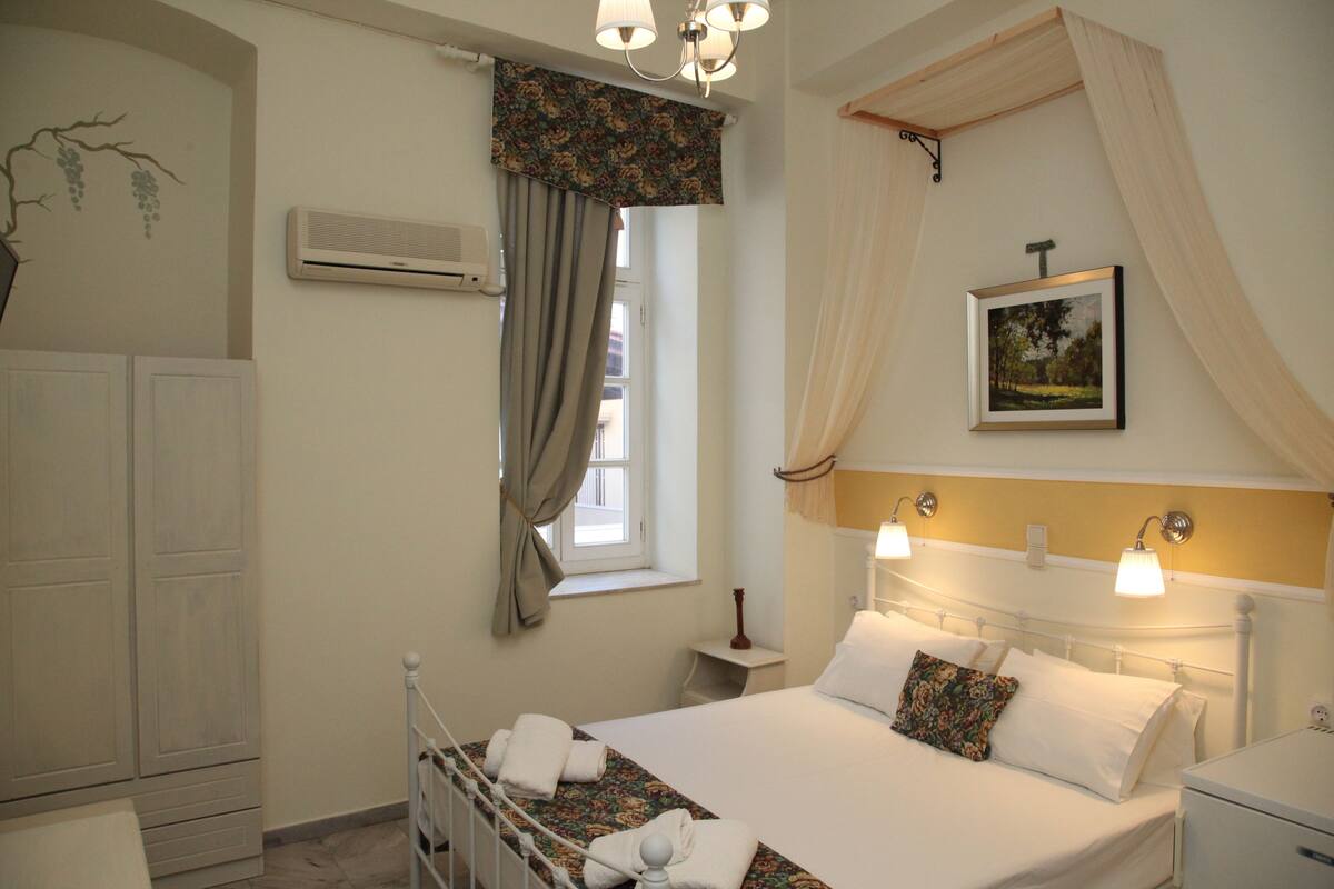 A bedroom with a bed, bedside table, and a window with curtains.
