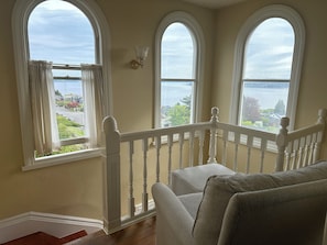 A room with a balcony, large arched windows, and a view of a body of water.