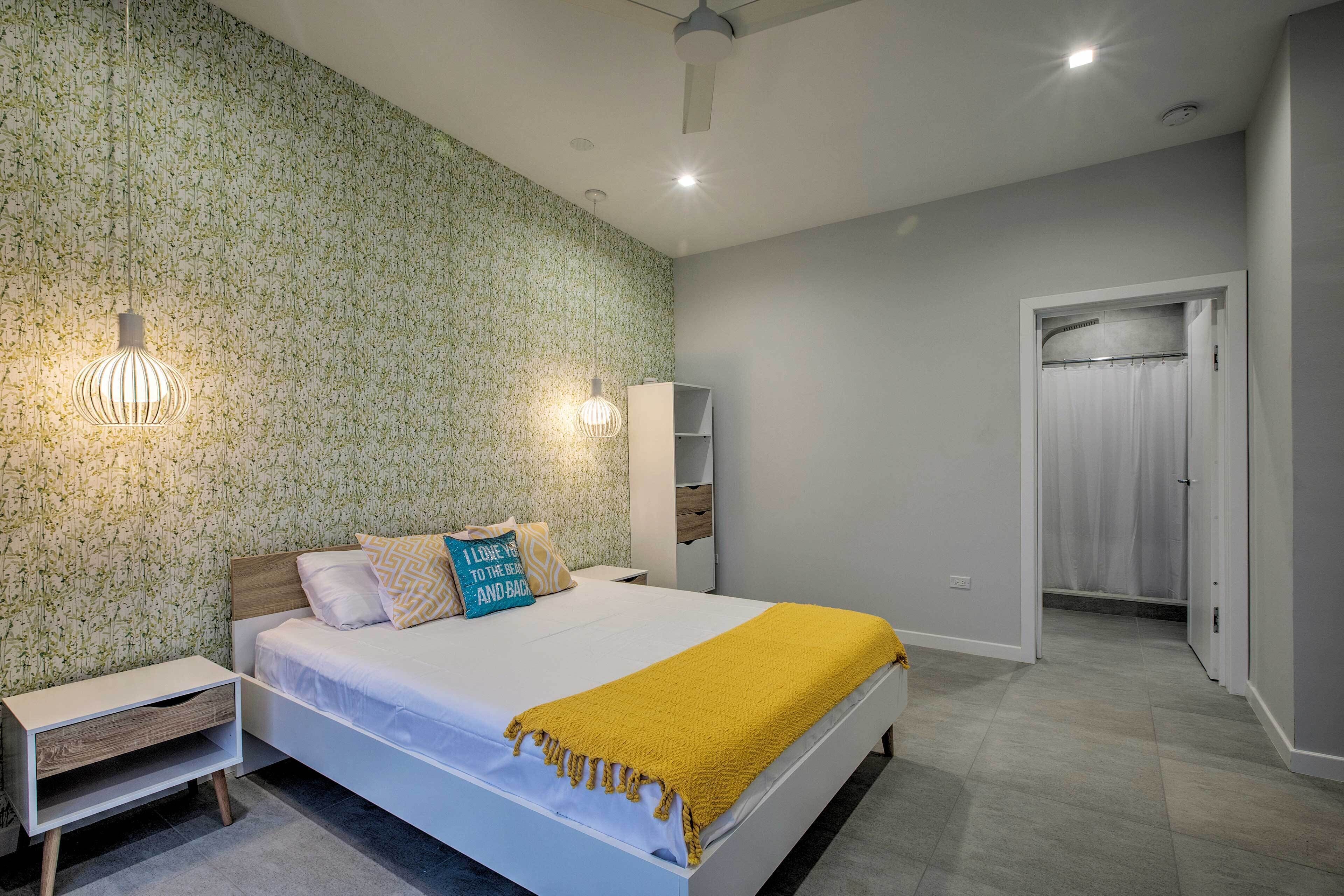 A bedroom with a bed, nightstands, a wardrobe, and a bathroom door.