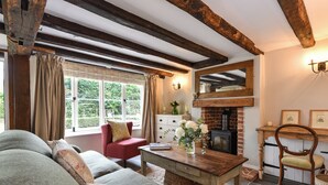A cozy living room with a fireplace, a sofa, a table, and a chair. - 2 bedroom accommodation in Cheriton (Cheriton)