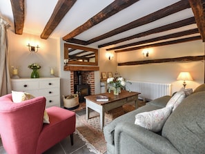 A cozy living room with exposed wooden beams, a fireplace, a white radiator, and a comfortable seating area. - 2 bedroom accommodation in Cheriton (Cheriton)