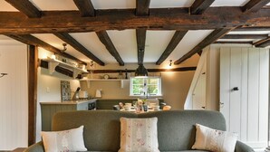 A cozy living room with a grey sofa, floral cushions, and a wooden ceiling. - 2 bedroom accommodation in Cheriton (Cheriton)
