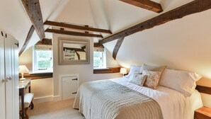 A bedroom with a large bed, a bedside table with a lamp, a window with a view, and a door. - 2 bedroom accommodation in Cheriton (Cheriton)