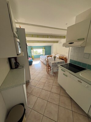 A kitchen with a microwave, a sink, and a dining area with a table and chairs.