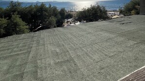 A view of a beach with a clear sky, a sun shining, and a distant mountain range.