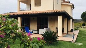 A two-story house with a covered patio area, a satellite dish, and a lawn. - Refined detached villa for nature lovers. (Domus De Maria)